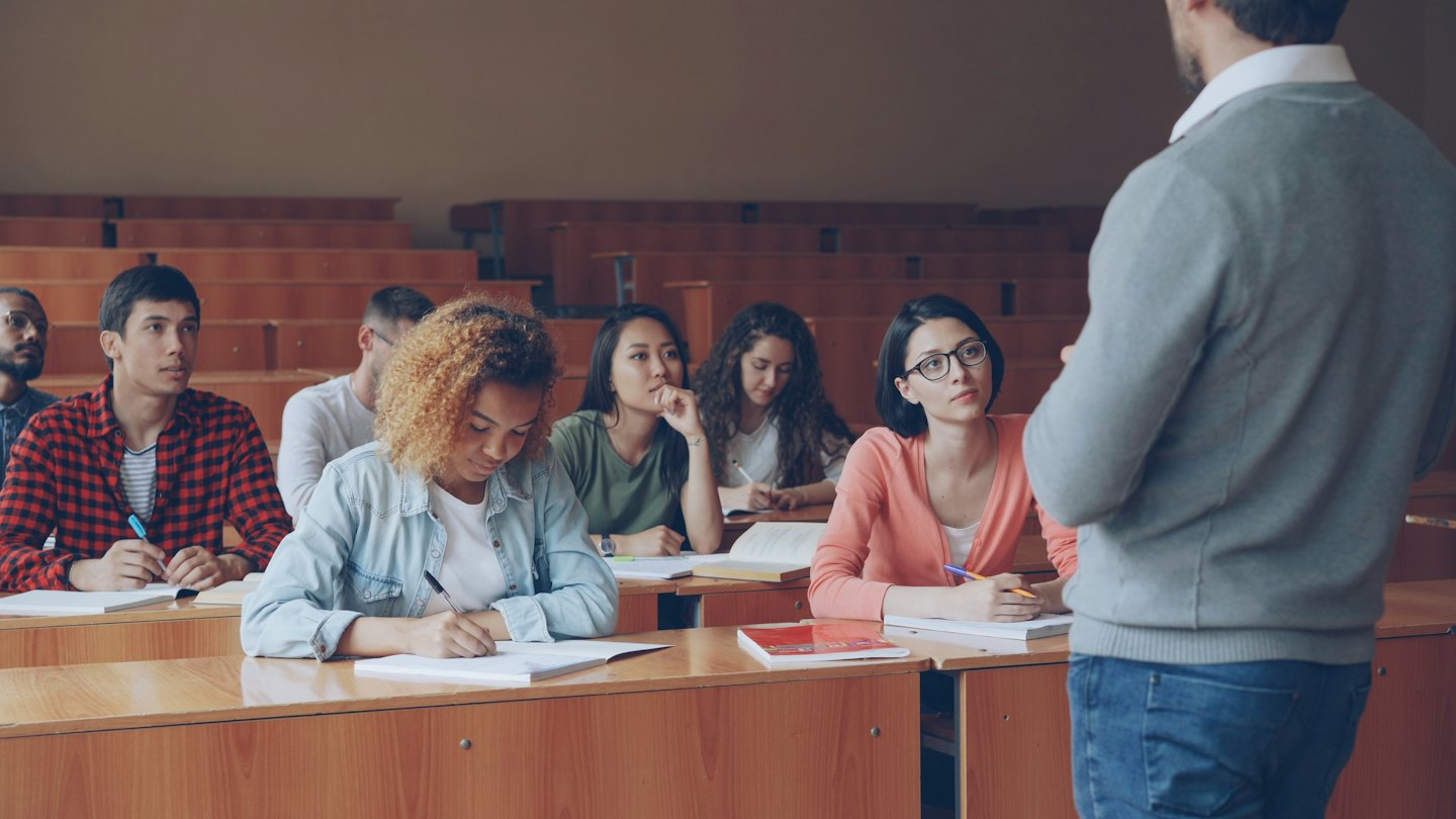 Studenten hören in einem Hörsaal aufmerksam einer Vorlesung zu.